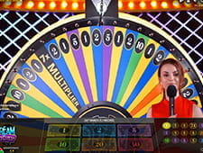 Das Bild zeigt ein Glücksrad, bei dem die Zahlen für die Multiplikatoren, mit denen der Einsatz verrechnet wird, stehen. Davor steht die Frau, die das Glücksrad in Gang setzt.