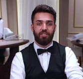 Das Bild zeigt einen Croupier mit Vollbart bei einer Runde Blackjack.