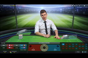 Das Bild zeigt das Live Spiel Football Studio, in dem ein Kartengeber an einem grün bezogenen Tisch sitzt, der wie ein Fußballfeld markiert ist.