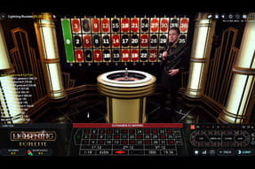 Das Bild zeigt den Moderator des aufregenden Live Titels Lightning Roulette im Studio an einem Roulettetisch. Hintergrundkulisse sind Zahlenreihen .