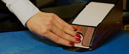 Die Hand eines Dealers, der eine Runde Blackjack austeilt.