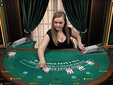 Das Bild zeigt eine blonde Dealerin an einem Blackjack Tisch. Sie gibt gerade den fünf anwesenden Spielern ihre Karten.