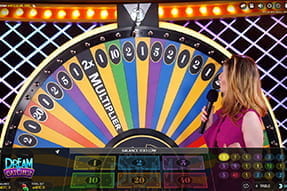 Das Bild zeigt das Glücksrad des beliebten Spieles Dreamcatcher nebendem die Moderatoren steht.