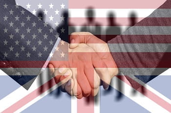 Handschlag vor der Kulisse der britischen und US-amerikanischen Flagge