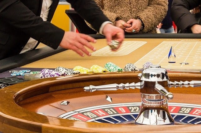 Mehrere Personen spielen an einem Roulette-Tisch.