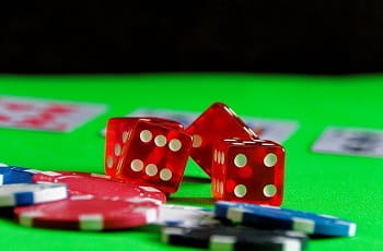 Spielwürfel, Pokerchips und Karten auf einem Casinotisch.