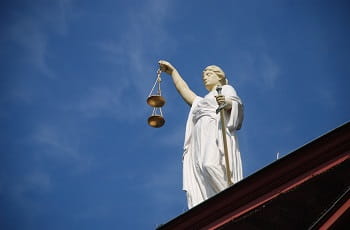 Eine Staue der Justitia auf einem Gebäude.