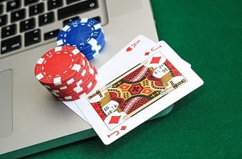 Spielkarten und Pokerchips auf einer Laptoptastatur.