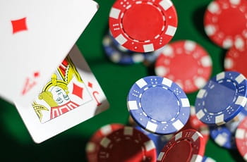 Spielkarten und Pokerchips fallen auf einen Spieltisch.