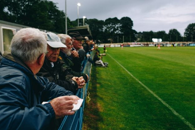 Menschen haben Spaß und schauen bei Kreisliga Spiel zu.