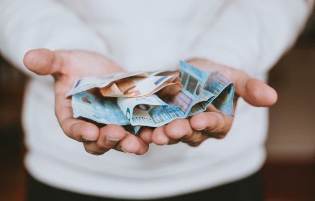 Geld auf der Hand welches Spenden-Gelder symbolisiert.