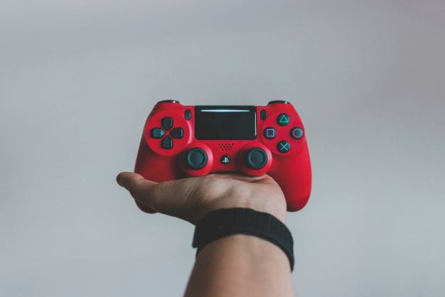 Roter Controller auf der Hand als Symbol für die Videospiele-Sucht.