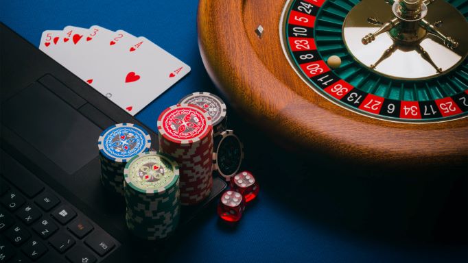Poker Chips, Roulette und Laptop als Symbol für Online-Glücksspiel.