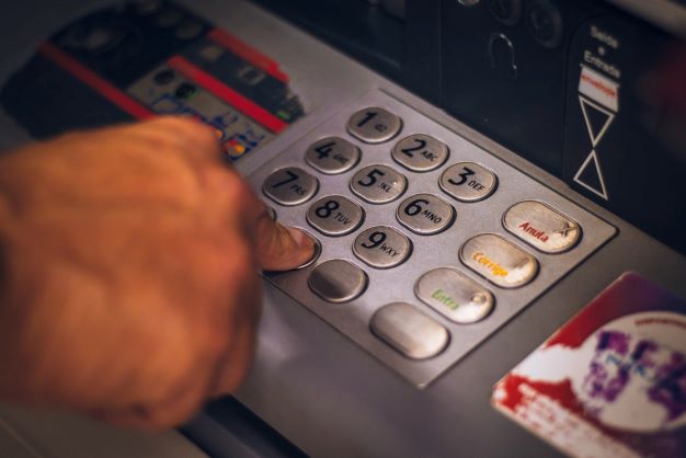Mann am Geldautomaten als Symbol für die Bonitätsprüfung seitens der Glücksspiel-Anbieter.
